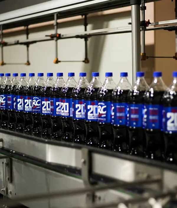 Close-up of RC Cola bottles on a conveyor belt during the bottling process